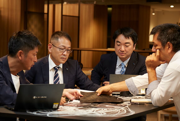 写真：チームのメンバーと打ち合わせをする船橋 直人・武田 忠・大久保 恵介