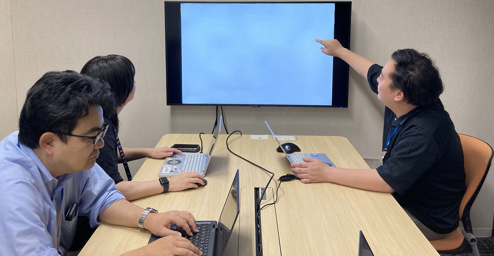 社員がPCとモニターを使いながら打ち合わせを行う様子