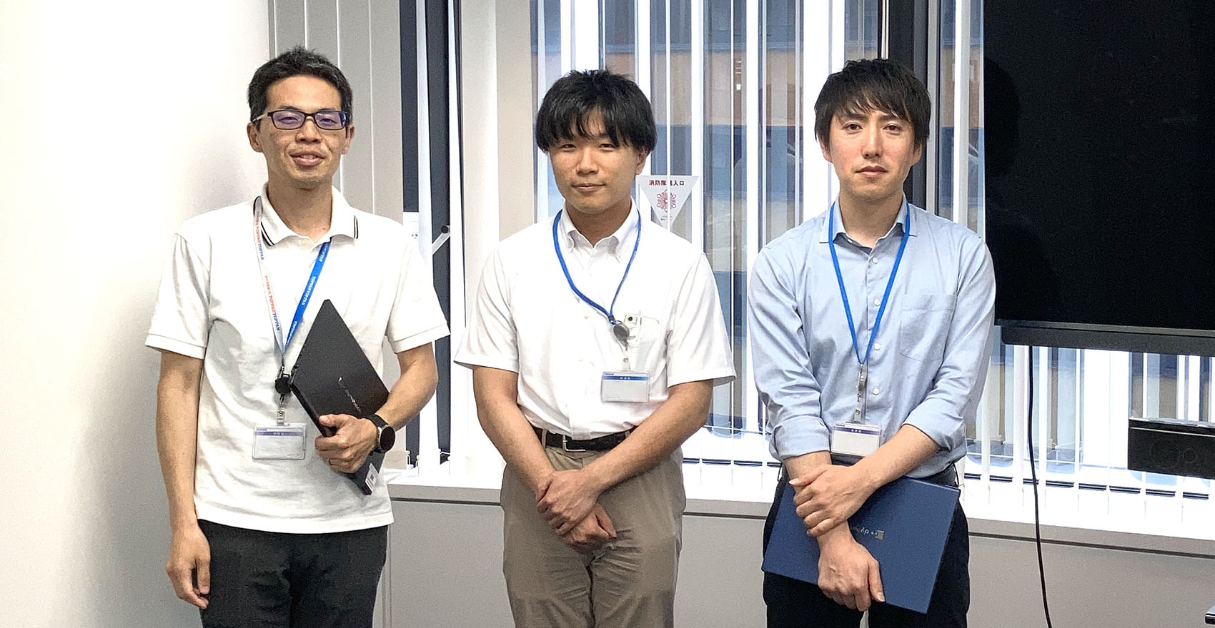 男性社員3名が並んで立っている集合写真