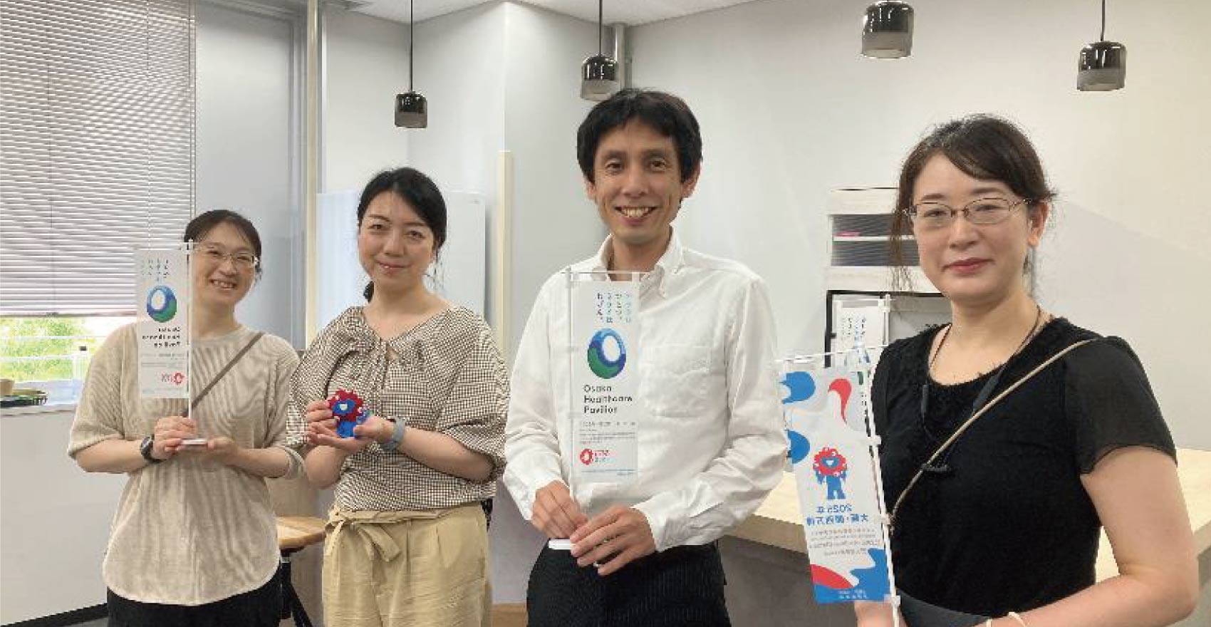 男性社員1名と女性社員3名が正面を向いて並んで笑顔をむける様子