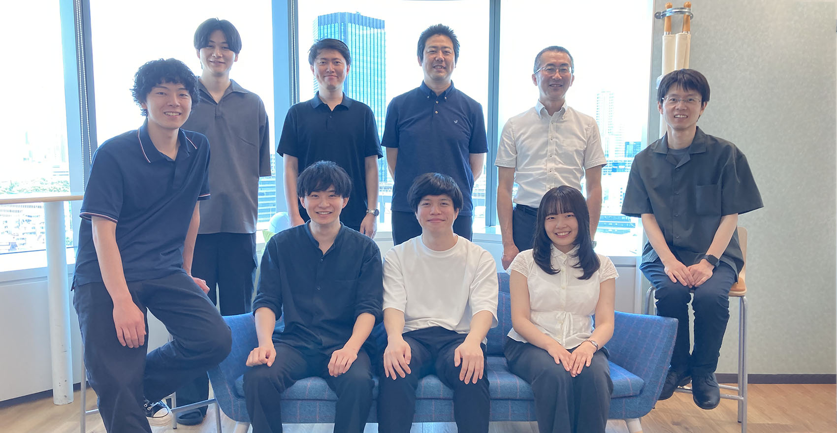 男性社員8名、女性社員1名の計9名が並んだ集合写真