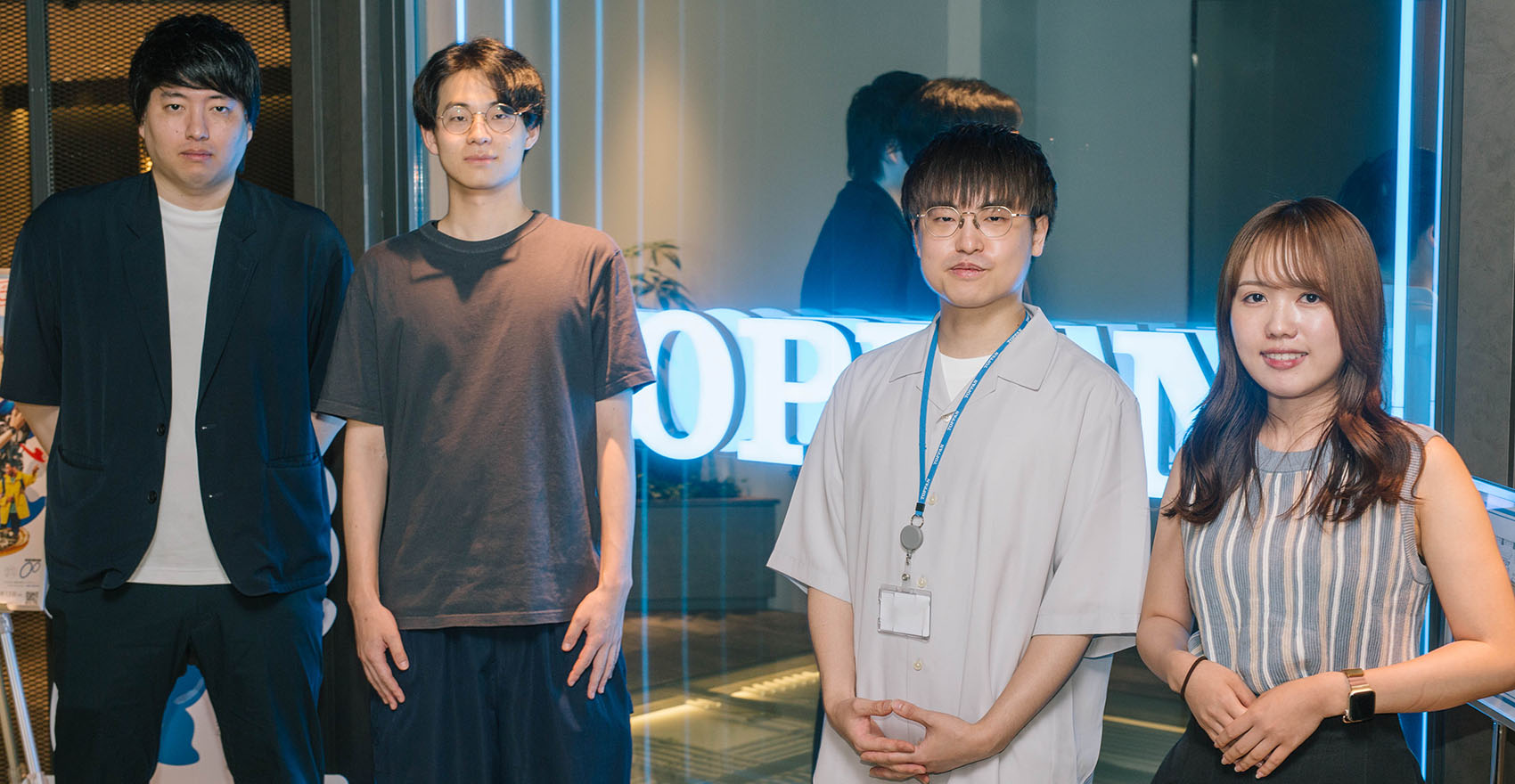 男性社員3名と女性社員1名が正面を向いて並んで立っている