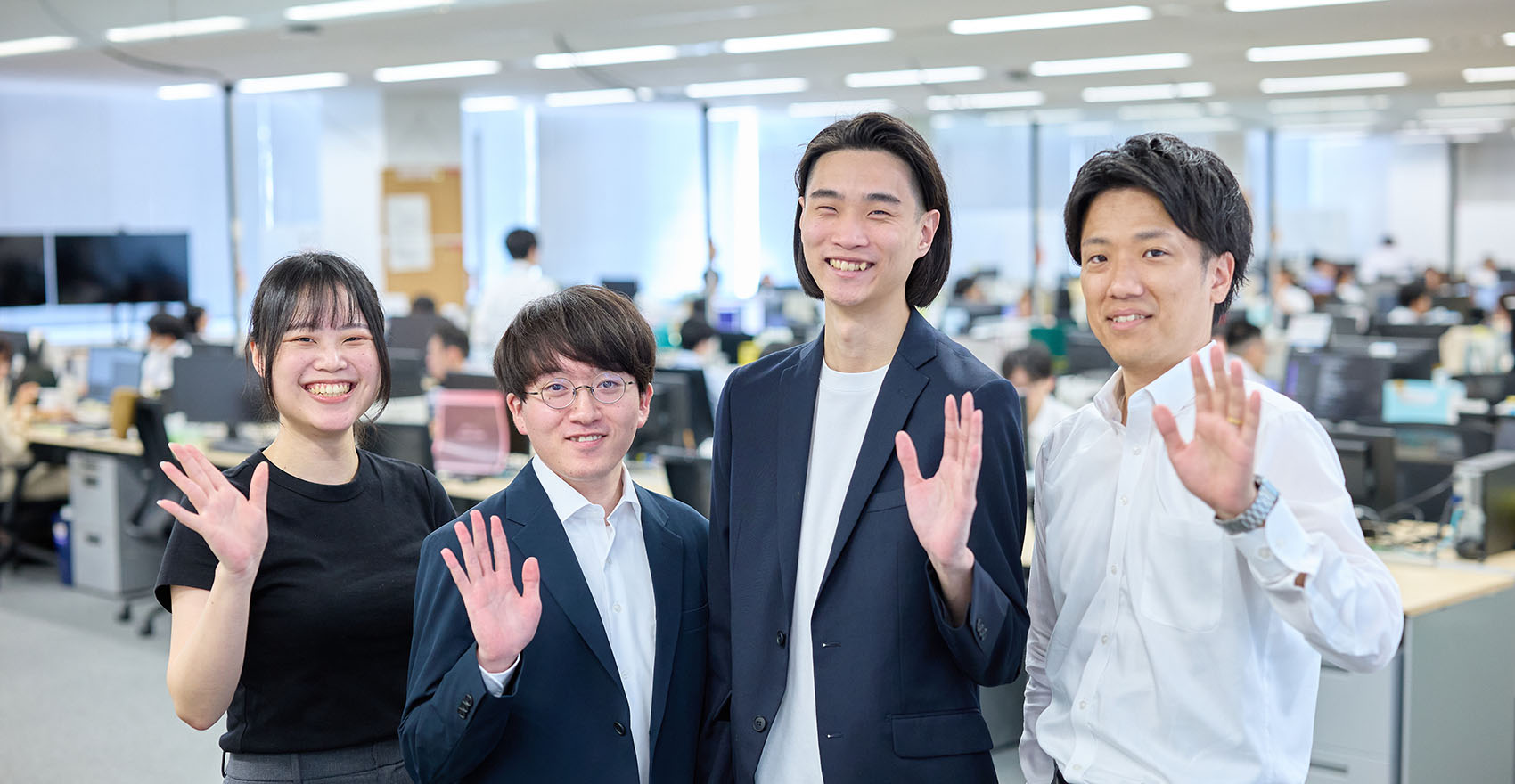 男性社員3名と女性社員1名が正面を向いて並んで笑顔をむける様子