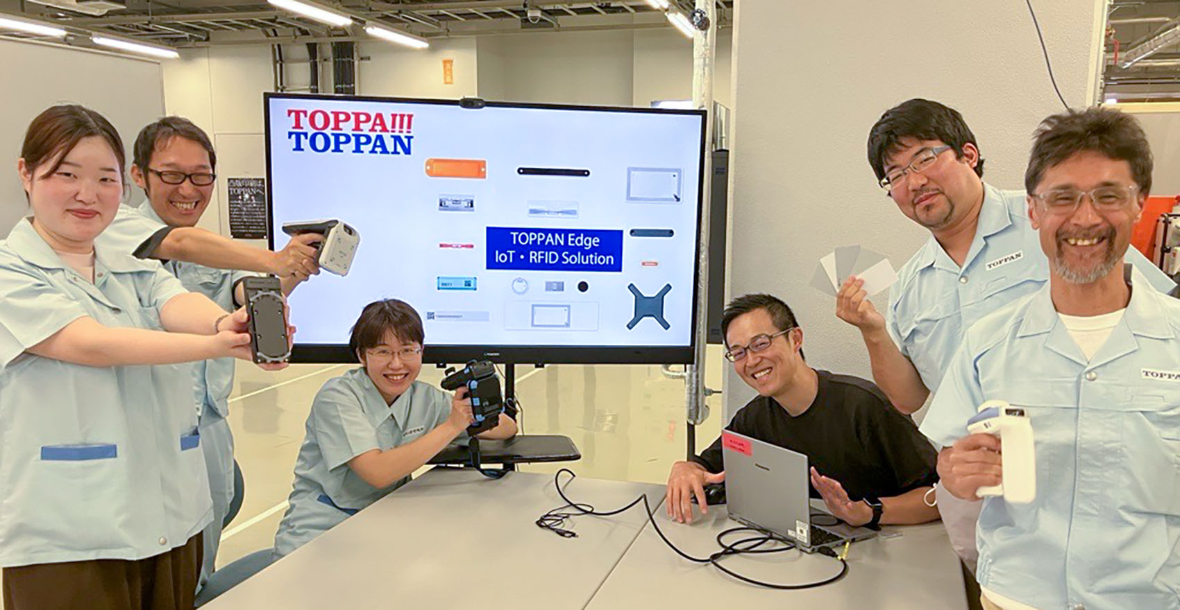 男性社員4名と女性社員2名が正面を向いて並んで笑顔をむける様子