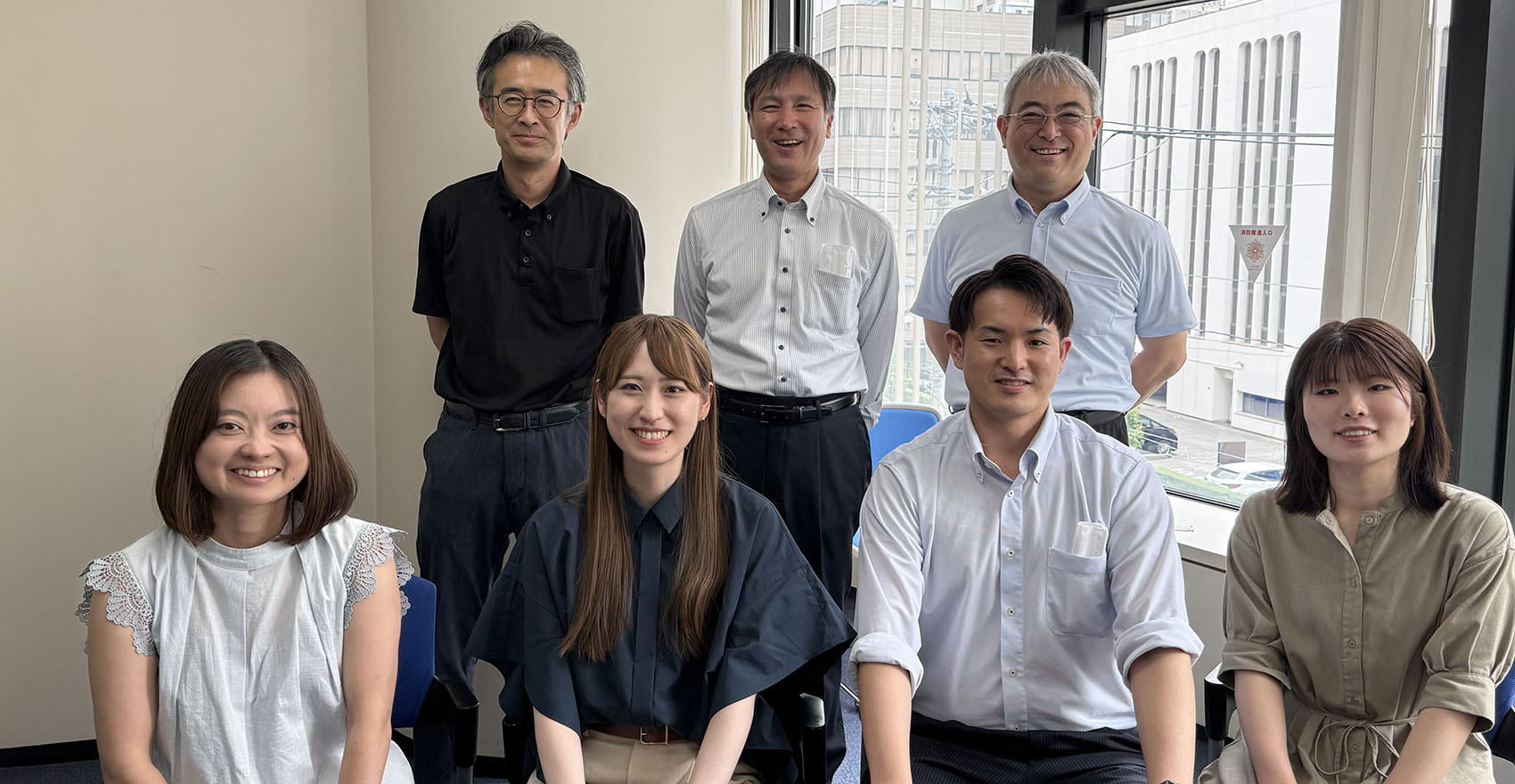 窓の前で笑顔でポーズをとる人々のグループ