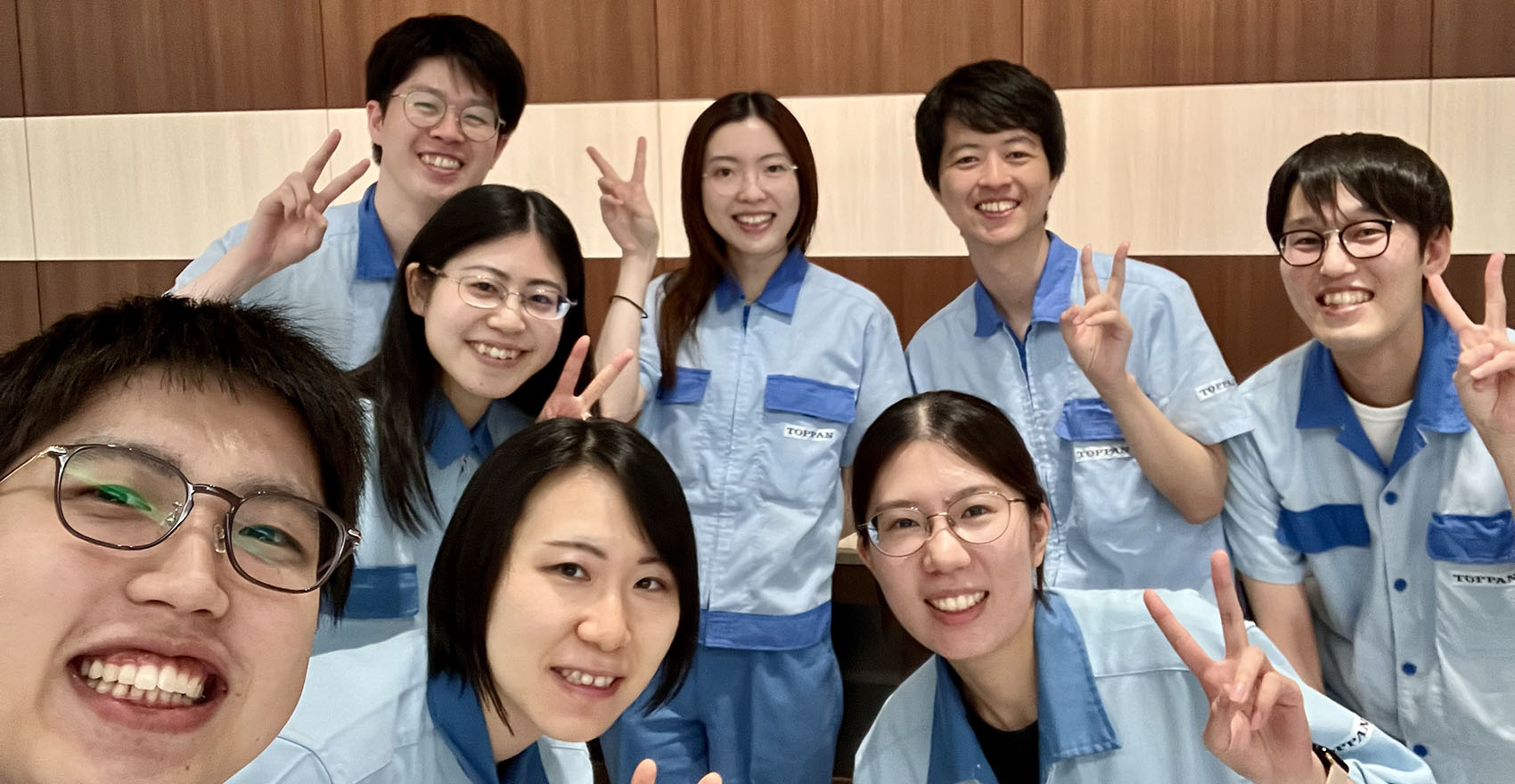 男性社員4名と女性社員4名がピースサインをして笑顔をむける様子