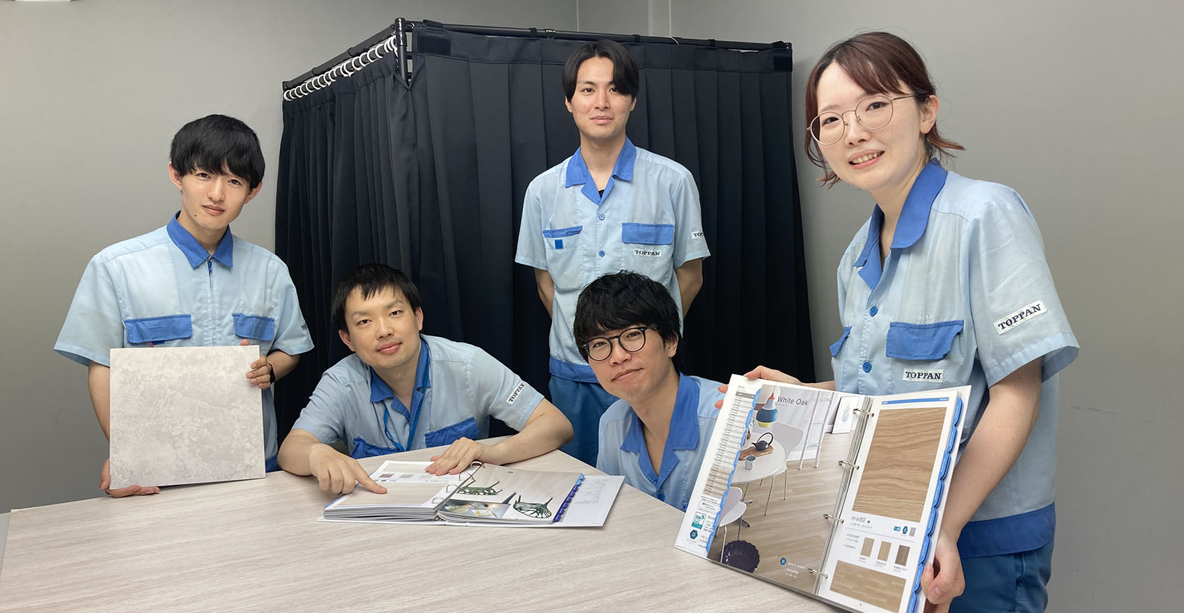 男性社員4名、女性社員1名が並んだ集合写真