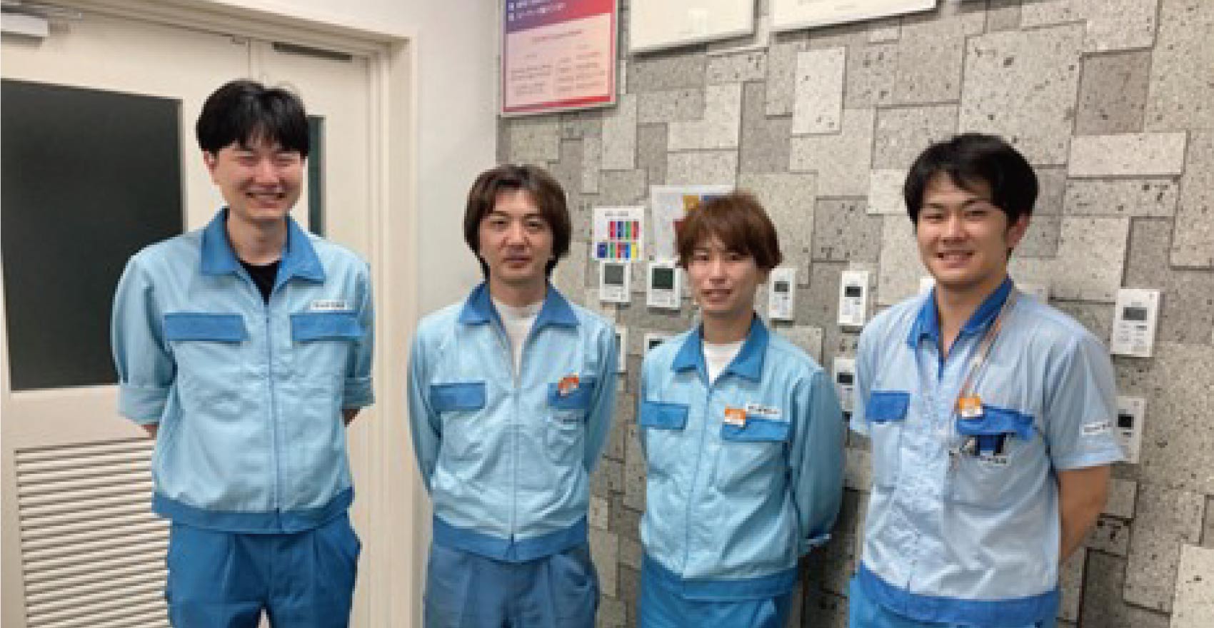 男性社員4名が正面を向いて並んで笑顔をむける様子