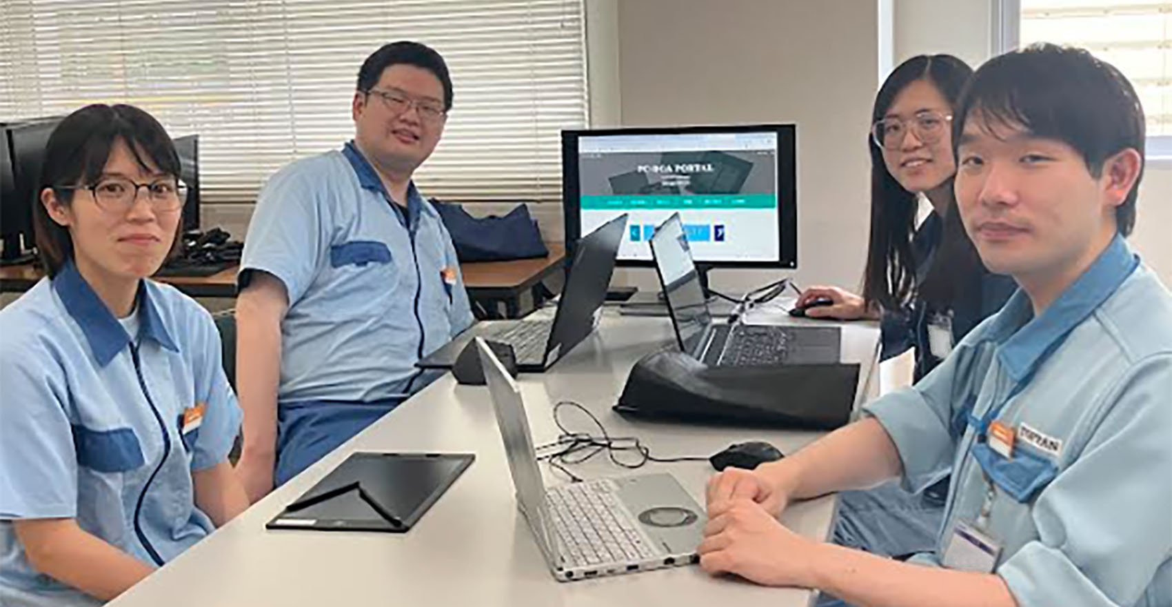 男性社員2名と女性社員2名が正面を向いて並んで笑顔をむける様子